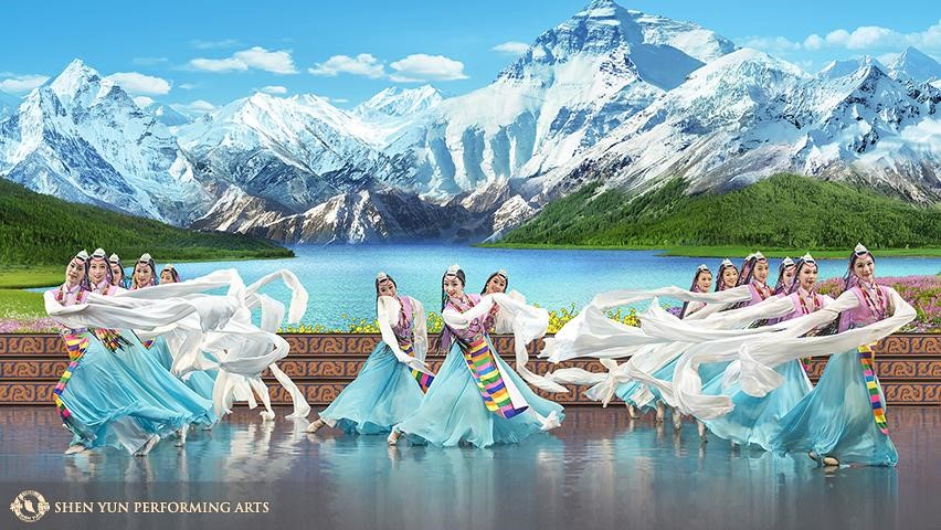 An image of a row of Chinese dancers in front of a beautiful mountain scene.