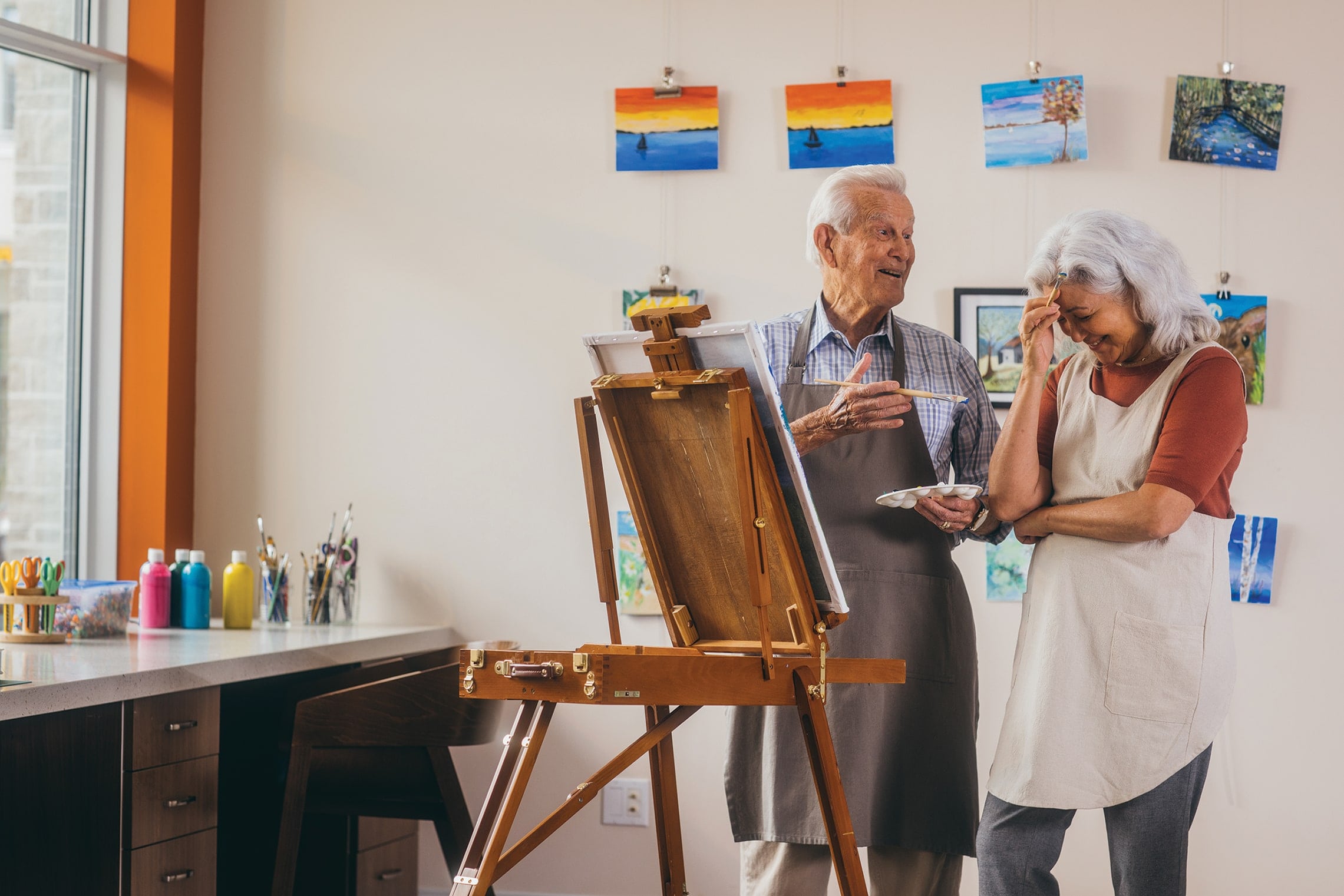 An image of two seniors laughing and painting.