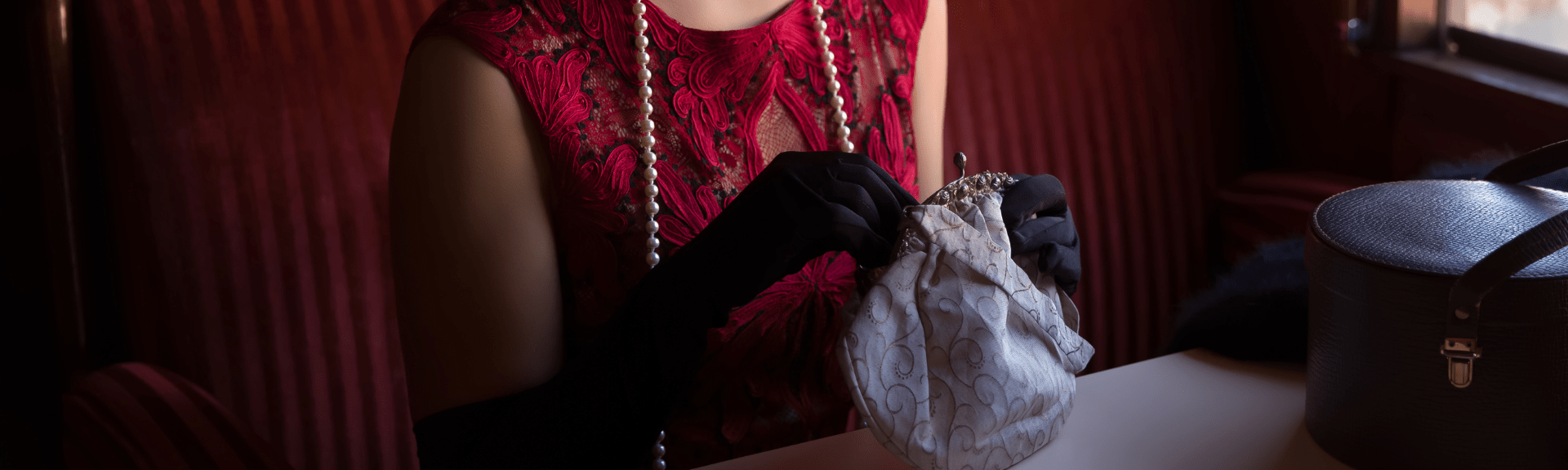 An image of a woman with pearls and a vintage purse.