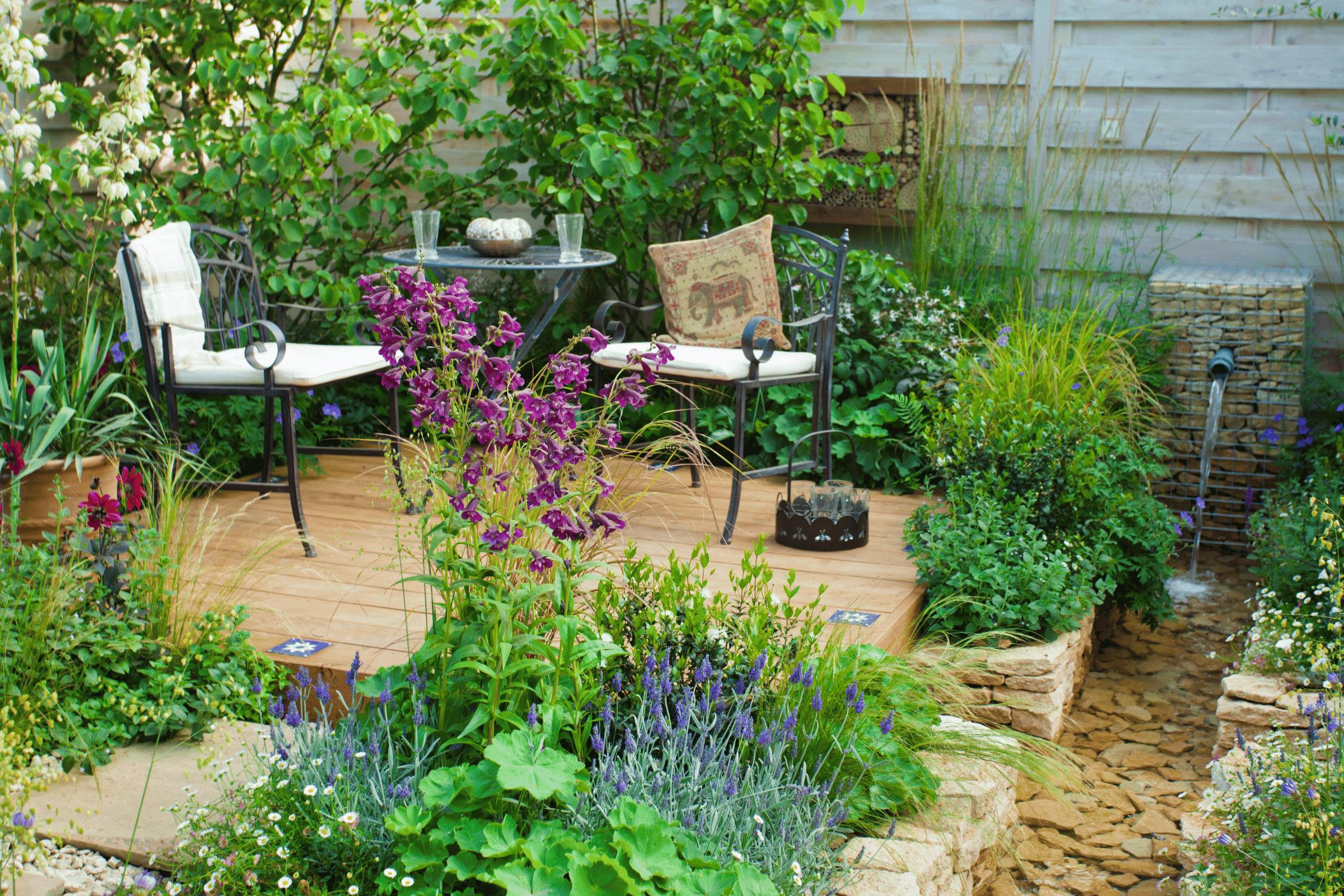 An image of a patio surrounded by plants and a garden.