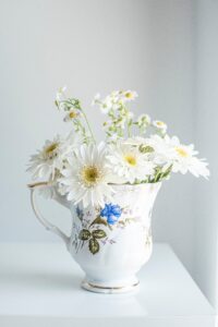 an image of white daisies in a vintage pottery vase